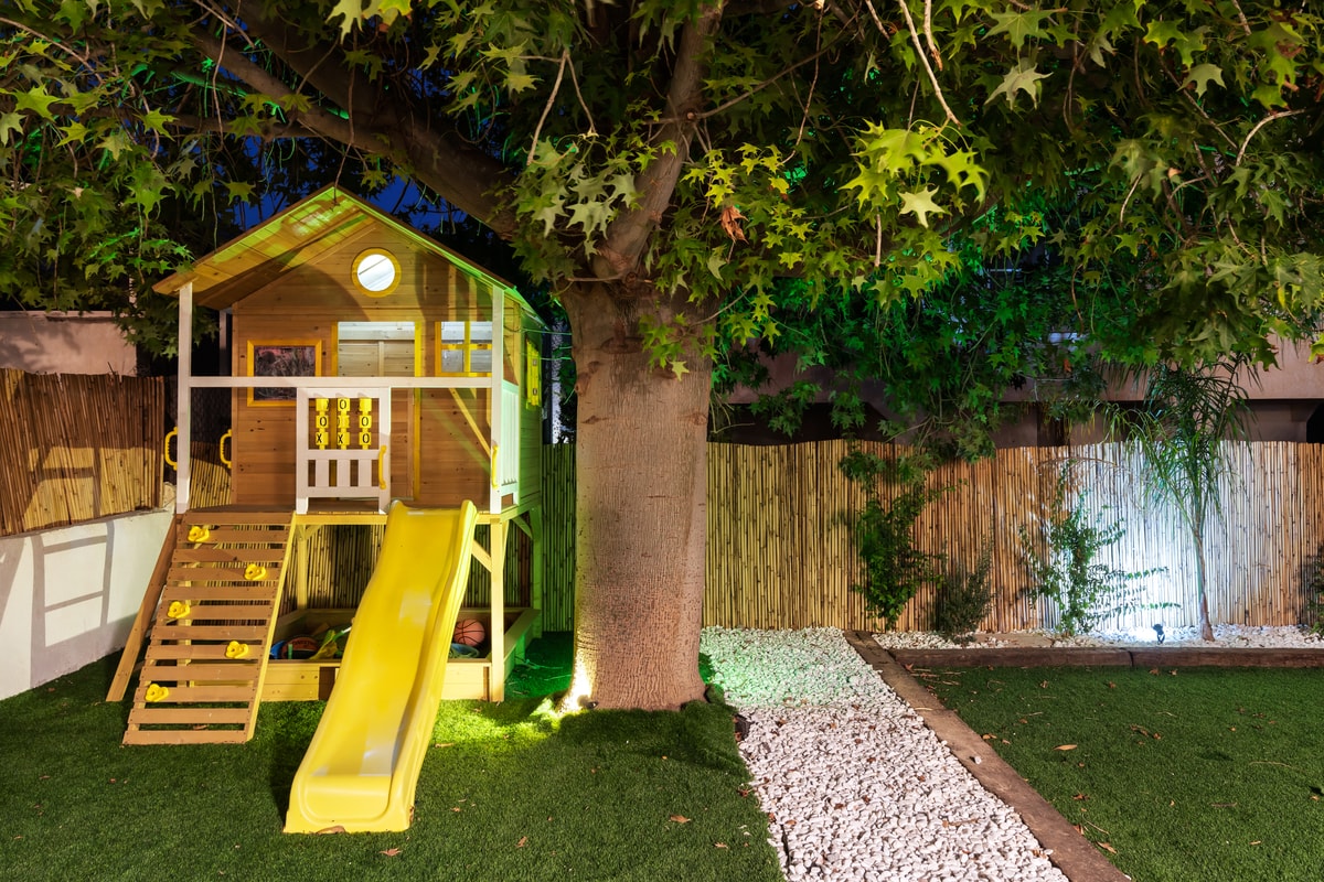 בית עץ לילדים עם מגלשה בגינה ירוקה