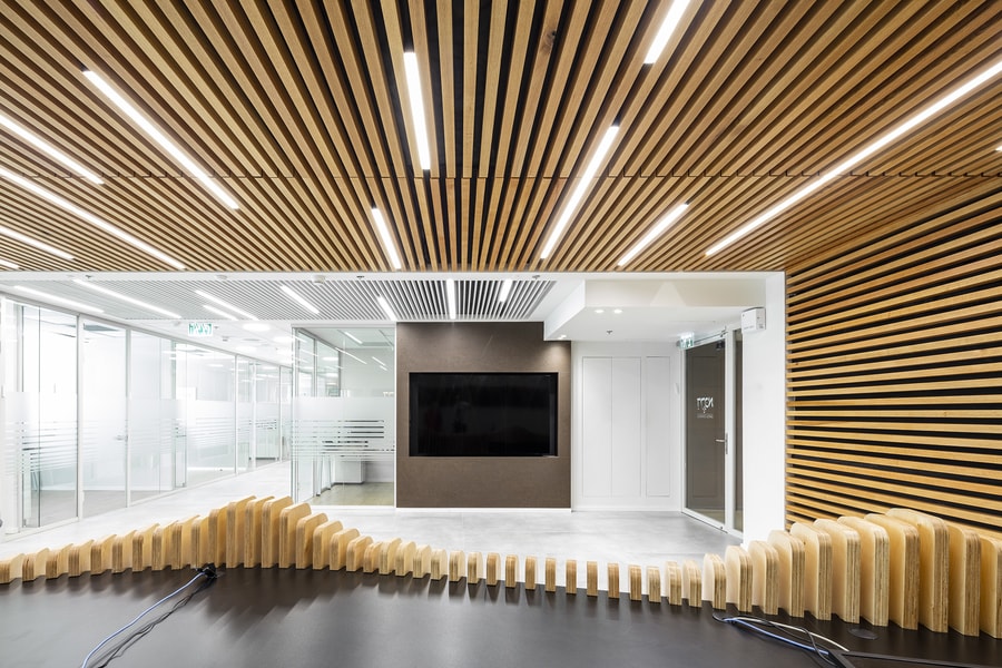 לובי משרדים מעוצב עם קיר ותקרה מלייסטים וגופי תאורה מעוצבים